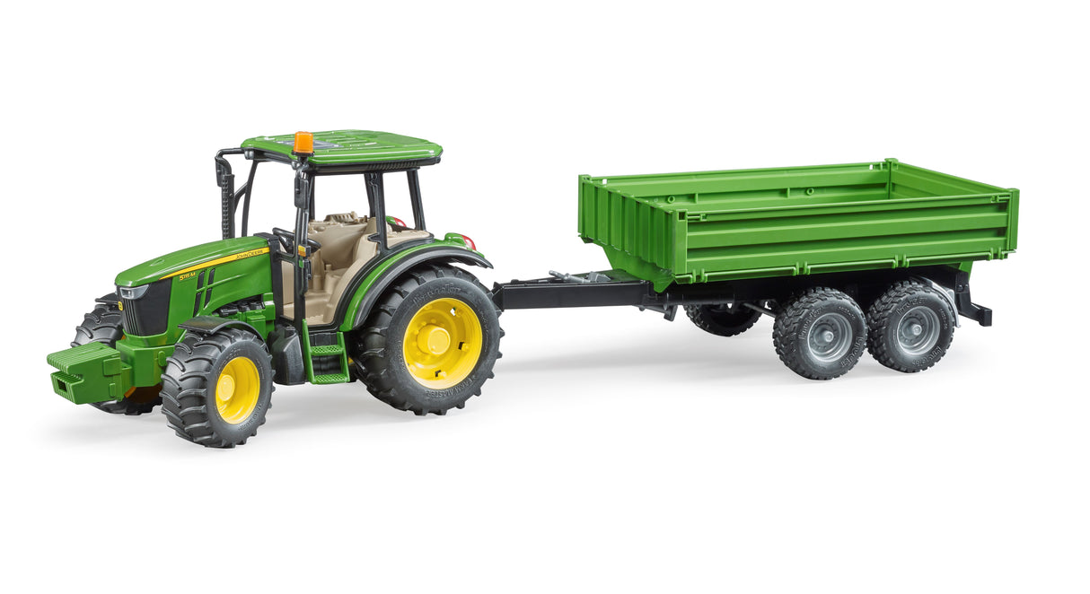 A John Deere 5115 M tractor with a tipping trailer, featuring a green and yellow color scheme, a steering wheel, and a tandem-axle trailer with fold-down side gates.