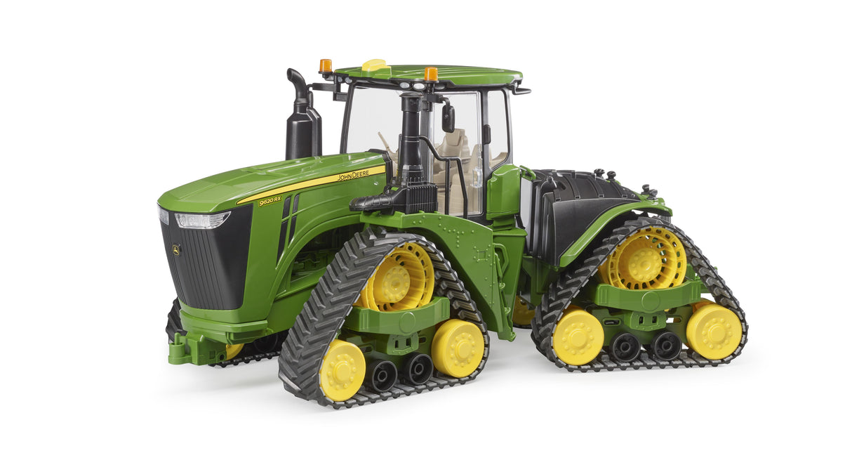 A John Deere 9620RX toy tractor with track belts, featuring a green and yellow color scheme, a large engine, and four wheels designed for off-road use.