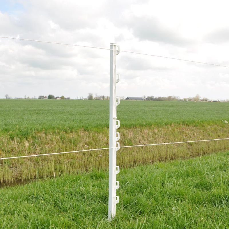A white plastic Gallagher Vario fence post with multiple lug positions, standing in a field with a few wires attached to it, used for electric fencing.