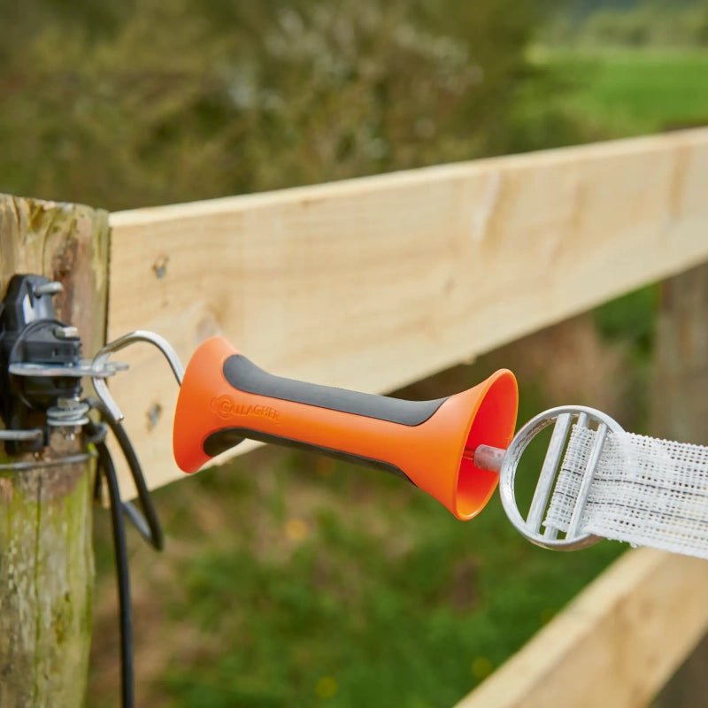 Orange and black gallagher soft touch handle attached to a wooden post with a blurred natural background