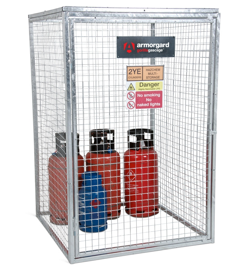 A galvanized metal security cage with mesh walls, containing several vertical gas cylinders.