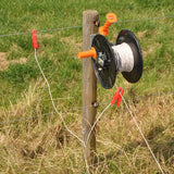 Fence wire reel with clips attached to a wooden post