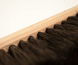 Close-up of a wooden broom with black bristles on a light background